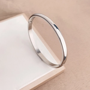 Dettaglio di un bracciale rigido minimalista in acciaio argentato con finitura lucida