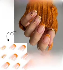 Detail of orange French press-on nails with golden glitter waves in coffin shape