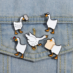 Detail of five funny enamel white duck brooches on blue denim jacket pocket