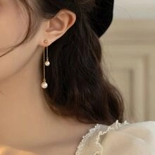 Gros plan sur les boucles d'oreilles pendantes en argent S925 avec perles blanches