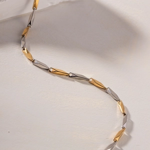 Macro detail of minimalist two-tone gold and silver geometric bamboo chain necklace
