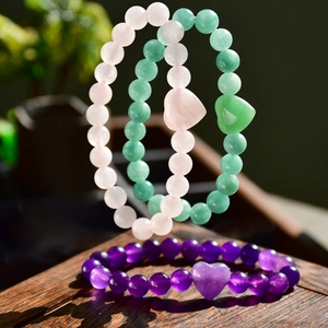 Close-up of amethyst and natural stone beaded bracelets with heart-shaped pendants