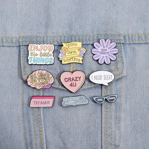 Set of 9 enamel pins with creative shapes on blue denim jacket pocket for fashion display