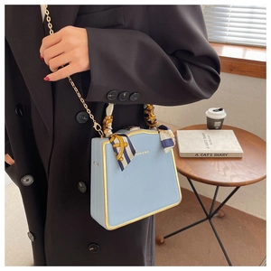 Detail of light blue box bag with gold metal trim and silk scarf wrapped handle