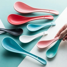 Macro detail of colorful ceramic spoons with hanging holes on a soft pastel background