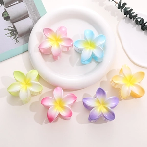 Top view of colorful gradient plumeria flower hair claws in pink blue and yellow