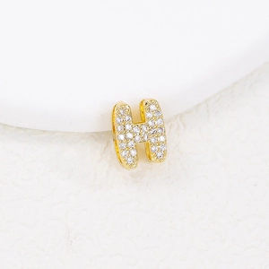 Macro shot of gold-plated letter H pendant with shimmering cubic zirconia inlay