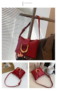 Detail of red leather crossbody bag featuring a signature large gold U-shaped metal buckle