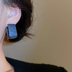 Macro shot of U-shaped blue zircon earrings on model showing fine stone pavé detail
