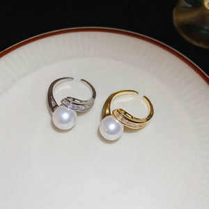 Gros plan de bagues serpent or et argent avec perles et pavé sur une assiette en céramique