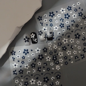 Detail of blue and white 3D flower nail stickers with pearl accents on grey background