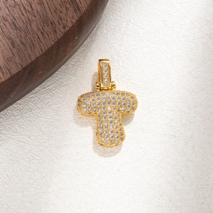 Macro shot of gold-plated letter T pendant with shimmering clear cubic zirconia stones