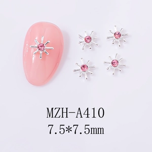 Macro detail of silver starburst nail charms with pink rhinestones for DIY nail art