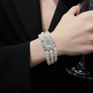 Detailed macro view of a three-row pearl bracelet with a sparkling clover diamond clasp