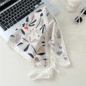 Detailed view of floral cotton triangle scarf with delicate white lace trim on a desk