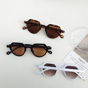 Three pairs of vintage round sunglasses in leopard, black, and white frames on white texture