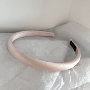 Detail of pink satin padded headband with hand made label on white tissue background