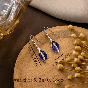 Detailed view of bohemian teardrop earrings with blue texture on a wooden tray
