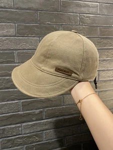 Detail of khaki fabric baseball cap with brown leather Hand Made tag on side