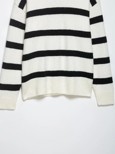 Detail view of black and white striped knit sweater with ribbed hem and fine texture