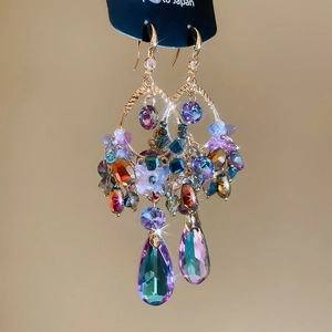 Close-up of bohemian earrings featuring multi-color crystals and teardrop pendants