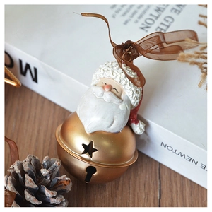 Close-up of a vintage golden Santa resin bell with ribbon on a cozy wooden table