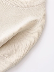 Detailed close-up of beige knit cardigan fabric with ribbed neckline and fine texture