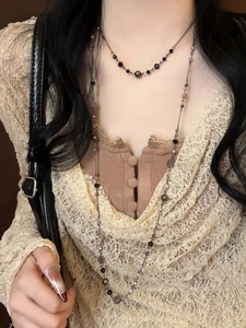 Close-up of double-layered beaded necklace with silver floral accents on lace garment