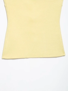 Detailed close-up of soft yellow knit fabric texture and hem stitching on women's top