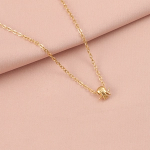 Detail of a dainty golden chain necklace featuring a small octopus pendant on pink fabric
