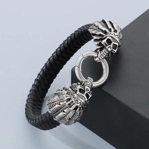 Close-up of black braided leather bracelet with engraved silver skull charms and clasp