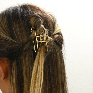 Elegant gold metal hair claw clip in minimalist cloud frame design on brunette hair