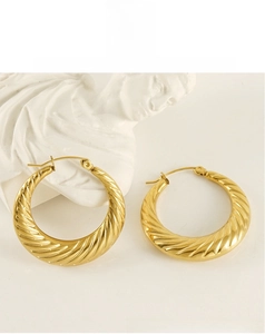 Detailed view of 18K gold plated chunky twisted hoop earrings on a minimalist white display