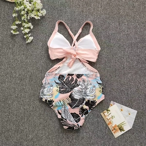 Flat lay of pink one-piece swimsuit with tropical leaf print and crisscross tie back