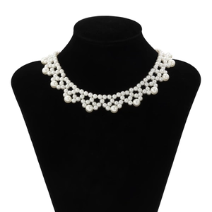 Detailed view of woven pearl choker necklace with large circular drops on a display stand