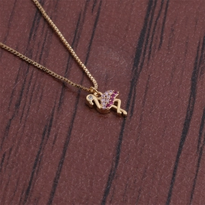 Macro shot of gold flamingo pendant with pink zircon crystals on a wooden background