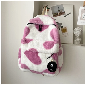 Close-up of pink and white faux fur backpack texture with fuzzy soot sprite pendant charm