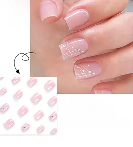 Detail of light pink French press-on nails with white lines and small rhinestones
