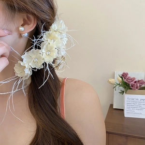 Détail de la pince à cheveux avec fleurs en dentelle, strass et plumes élégantes