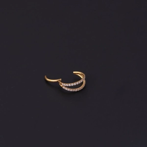 Detail of double-layer golden piercing ring with sparkling crystals on black background