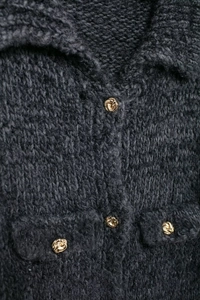 Gros plan détaillé du cardigan gris foncé en maille épaisse avec des boutons dorés texturés