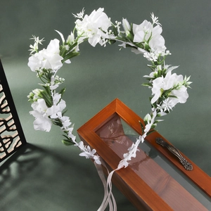 Close-up of white fabric flowers and green leaves bridal crown with ribbon tie