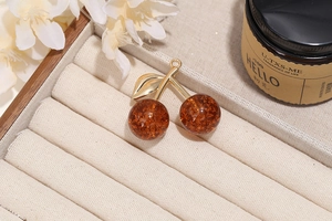 Close-up of realistic cherry pendant with amber resin fruit and golden metal leaf detail
