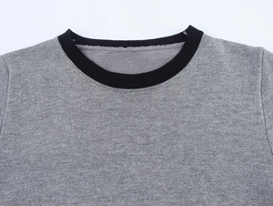 Détail du col rond contrasté en bord-côte noir sur un pull en tricot gris chiné