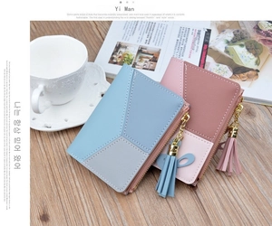 Detail of two-tone women's small wallets with tassel zipper and bow on a wooden table