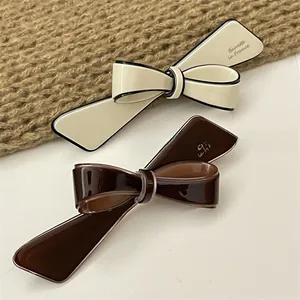 Detailed close-up of French style bow hair clips in cream and dark coffee colors