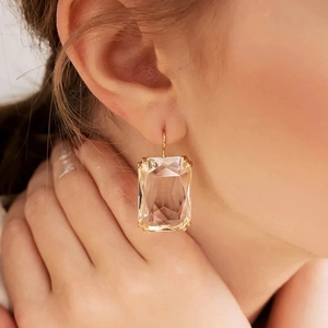 Elegante Goldohrringe mit großen rechteckigen transparenten Zirkonkristallen am Model