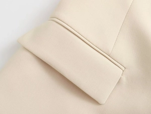 Detailed close-up of fine stitching and woven fabric texture on beige strapless suit pants