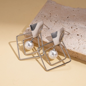 Silver geometric earrings with faux pearls and nested square frames on beige stone