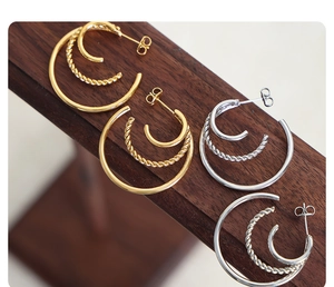 Macro detail of triple-layer C-shaped hoop earrings with polished and twisted textures